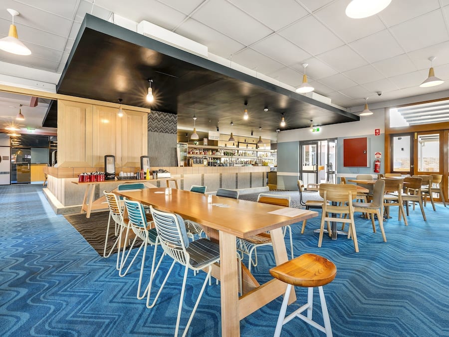 Une salle de conférence moderne, dotée d’une longue table, de chaises et d’un bar avec des étagères remplies de bouteilles.