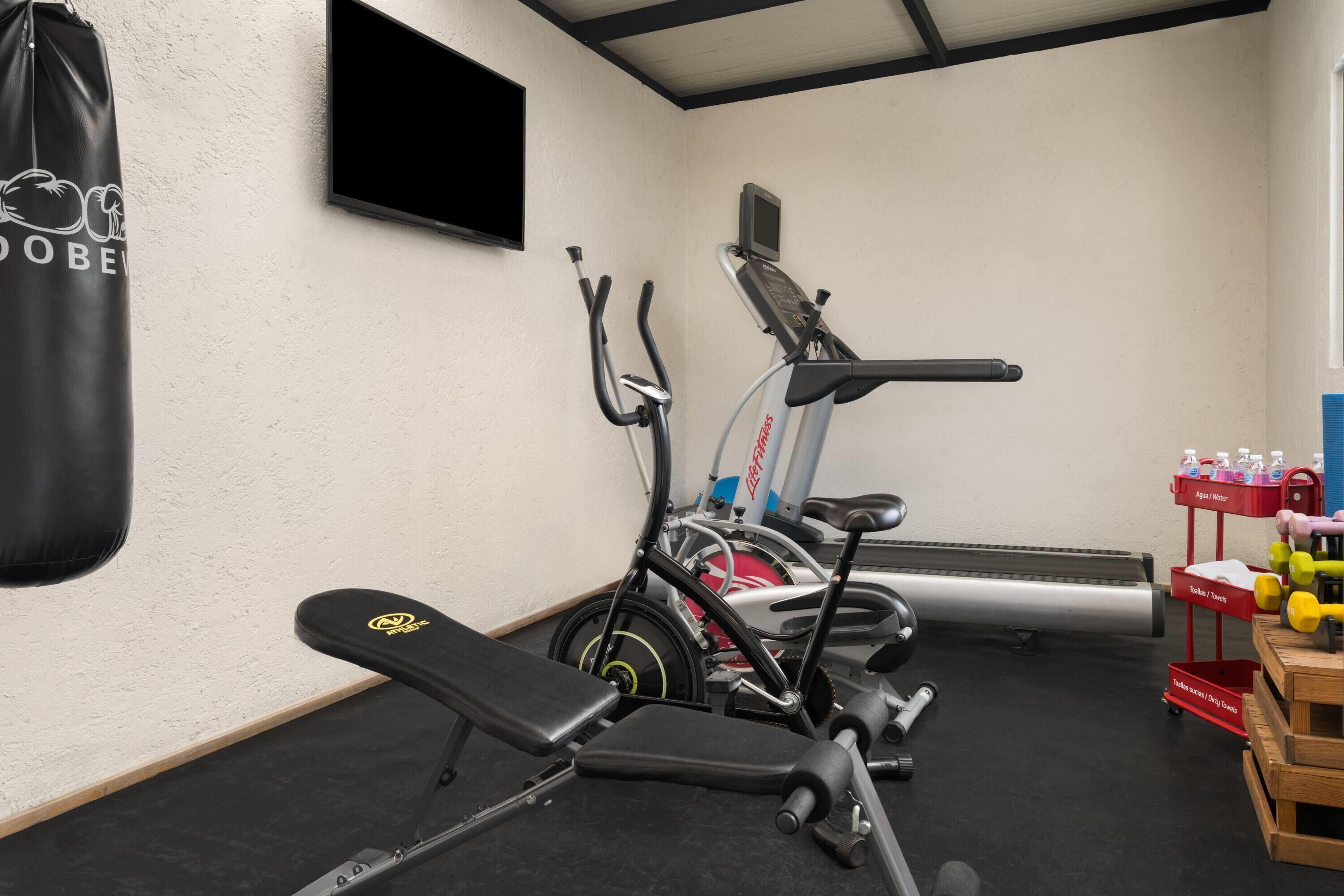 Een fitnessruimte met trainingsapparatuur, een bokszak en een waterpunt.