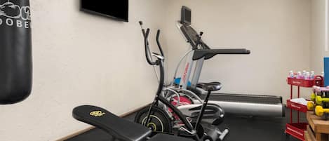 Een fitnessruimte met trainingsapparatuur, een bokszak en een waterpunt.