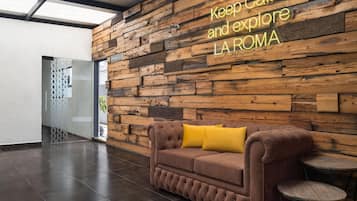 Un interior moderno con pared de madera, un sofá marrón y un cojín amarillo, junto a una pequeña mesa redonda.