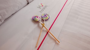 Een bed met een witte lakenset, twee kleurrijke lolly's en een rode streep.