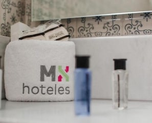 Een badkamer met een handdoekhouder, waarop een witte handdoek en een fles toiletartikelen liggen.