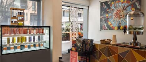 A cafe interior with a beverage display, a coffee machine, and a colorful mural.