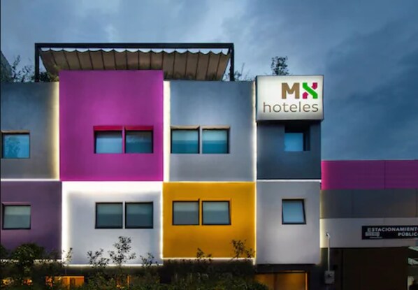 Un hotel de varios pisos con una fachada moderna que presenta paneles de colores distintos.