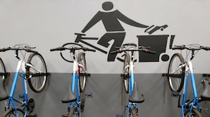 Een fietsenparkeerplaats met drie fietsen en een bordje dat een afvalcontainer aangeeft.