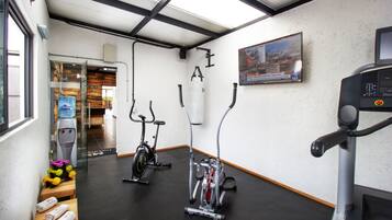 Un gimnasio con equipo cardiovascular, dispensador de agua y cinta de correr.