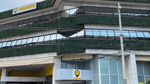 Un immeuble à plusieurs étages doté de balcons couverts de plantes vertes, une enseigne indiquant « Central del Norte » et un logo pour « ESCALA ».