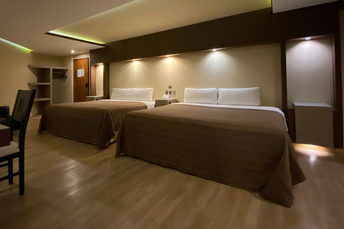 Ein Hotelzimmer mit zwei Betten, einem Schreibtisch und einem Stuhl.