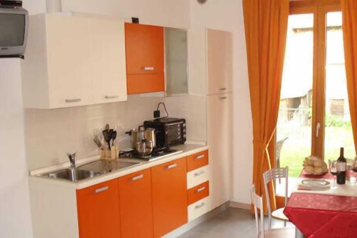 A compact kitchen with orange cabinets, a toaster, and a dining area with a table set for two.