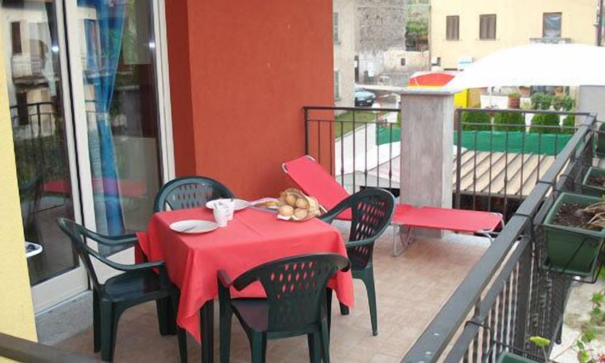 Un balcon avec une table dressée pour deux personnes, des chaises et une nappe rouge.