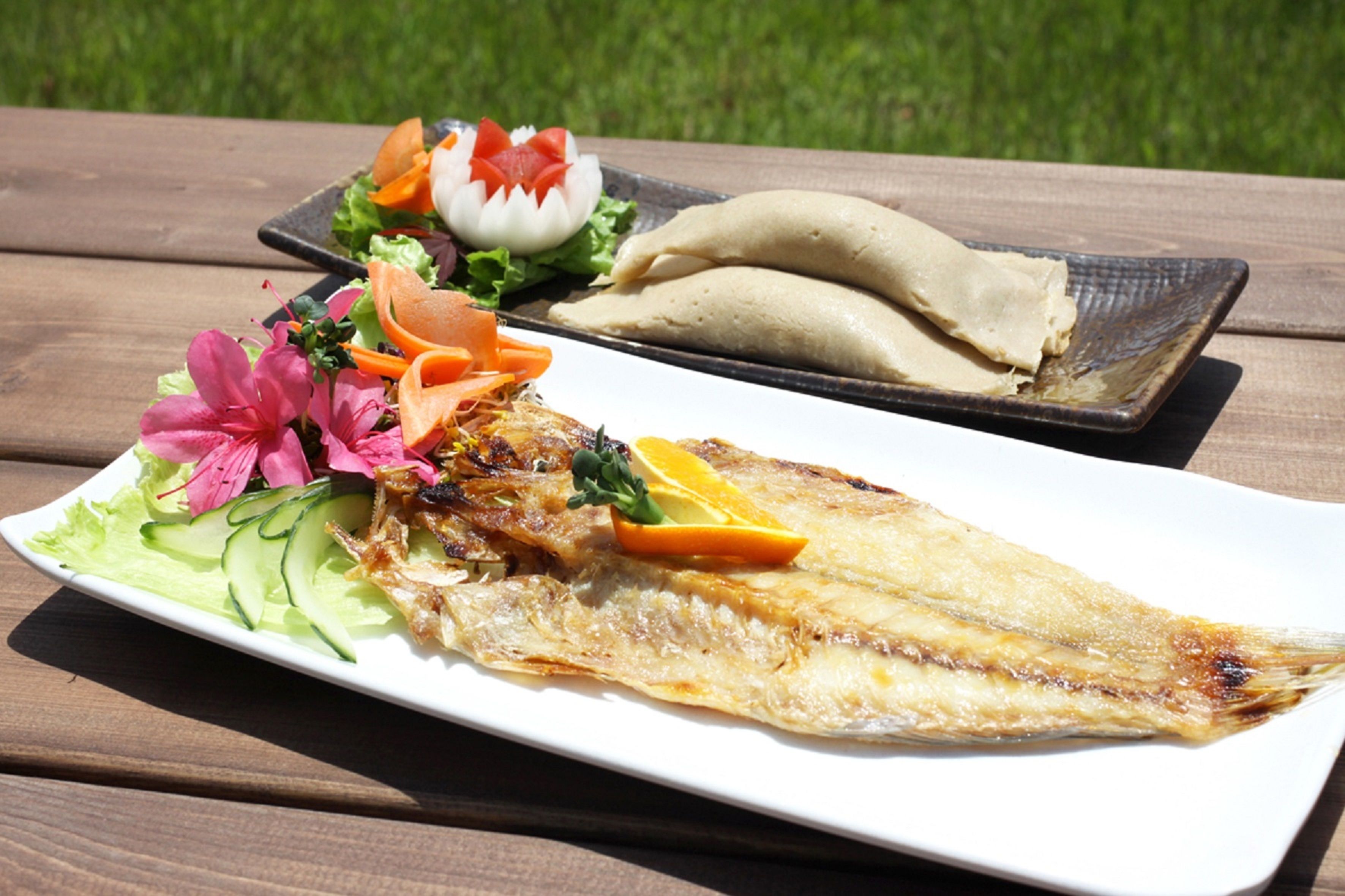 Pescado a la parrilla en un plato blanco, acompañado de una ensalada y una porción de tortillas.