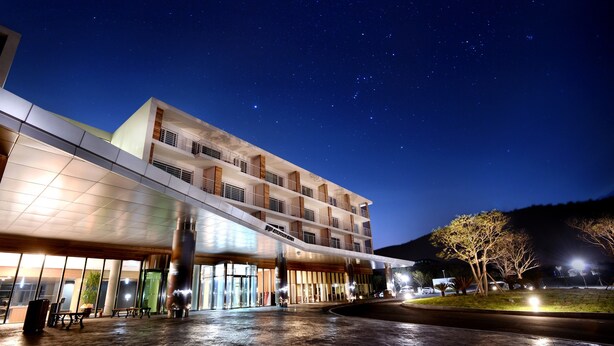 Un hotel moderno con una entrada espaciosa, amplias ventanas y un área exterior bien iluminada.