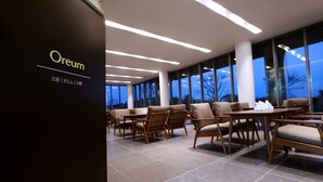 Un moderno vestíbulo de hotel con mostrador de recepci ón, zona de estar y grandes ventanales con vistas al exterior.