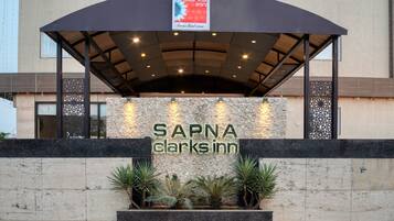 The exterior of SAPNA Clark's Inn with a covered entrance, stone facade, and decorative plants.