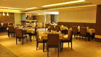 Un restaurant doté de nombreuses tables et chaises, d’un plafond haut avec des luminaires encastrés et d’un aménagement intérieur moderne.