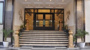A hotel entrance with a grand double door, steps leading up to it, and decorative columns on either side. - Sapna Clarks Inn (Lucknow)