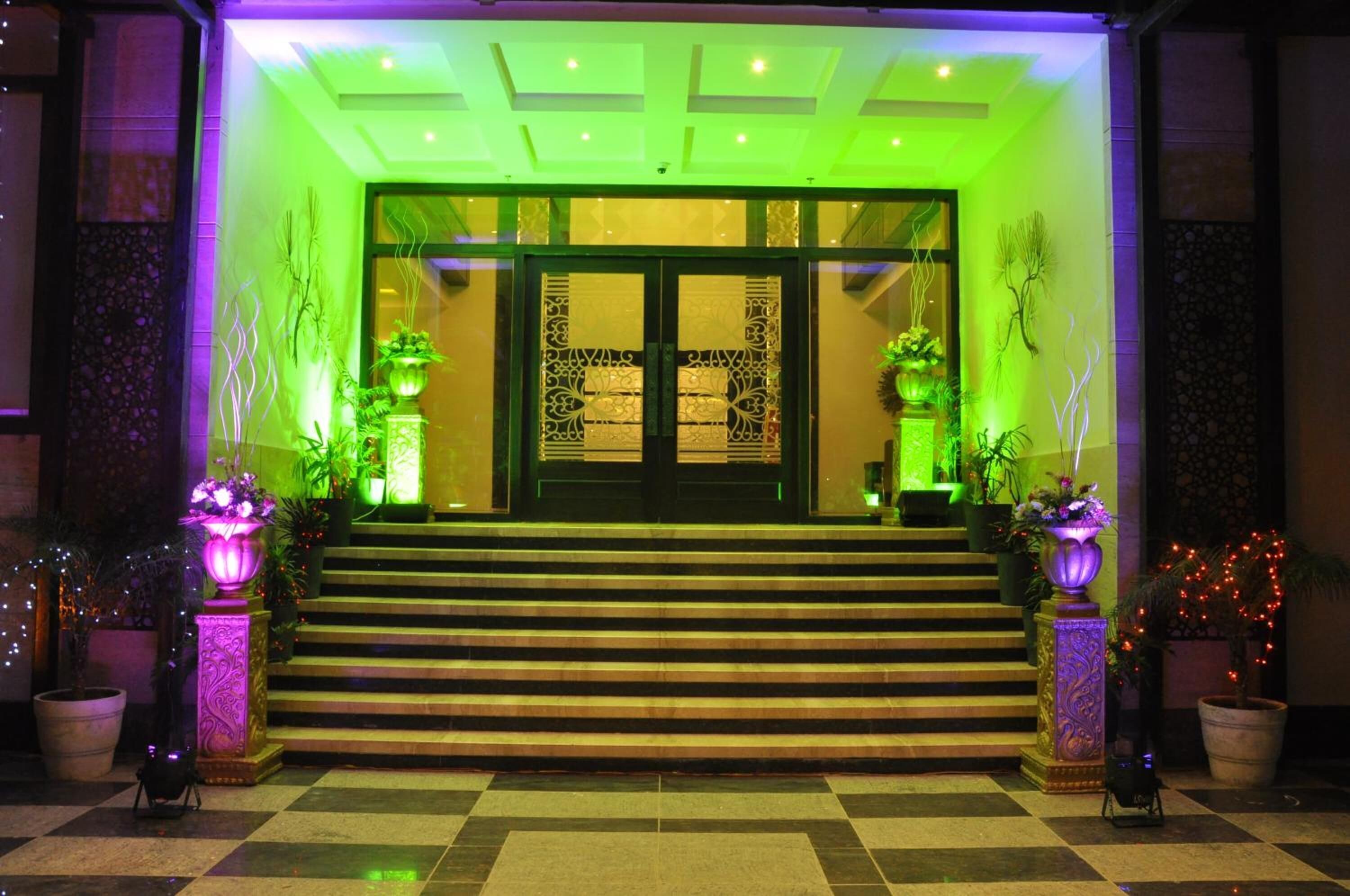 A hotel entrance with a checkered floor, steps leading up to a double door, and decorative lighting.