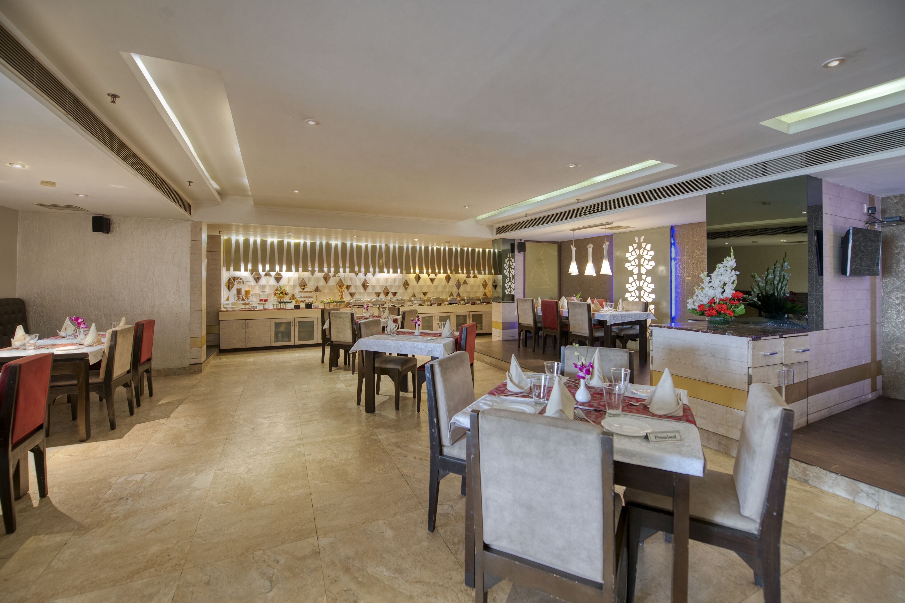 Ein geräumiges Restaurant mit mehreren Tischen, Stühlen und einer Bar im Zentrum, sowie einem modernen Deckenstil.