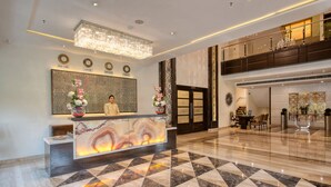A hotel lobby with a reception desk, a chandelier, a check-in counter, and a check-out counter. - Sapna Clarks Inn (Lucknow)