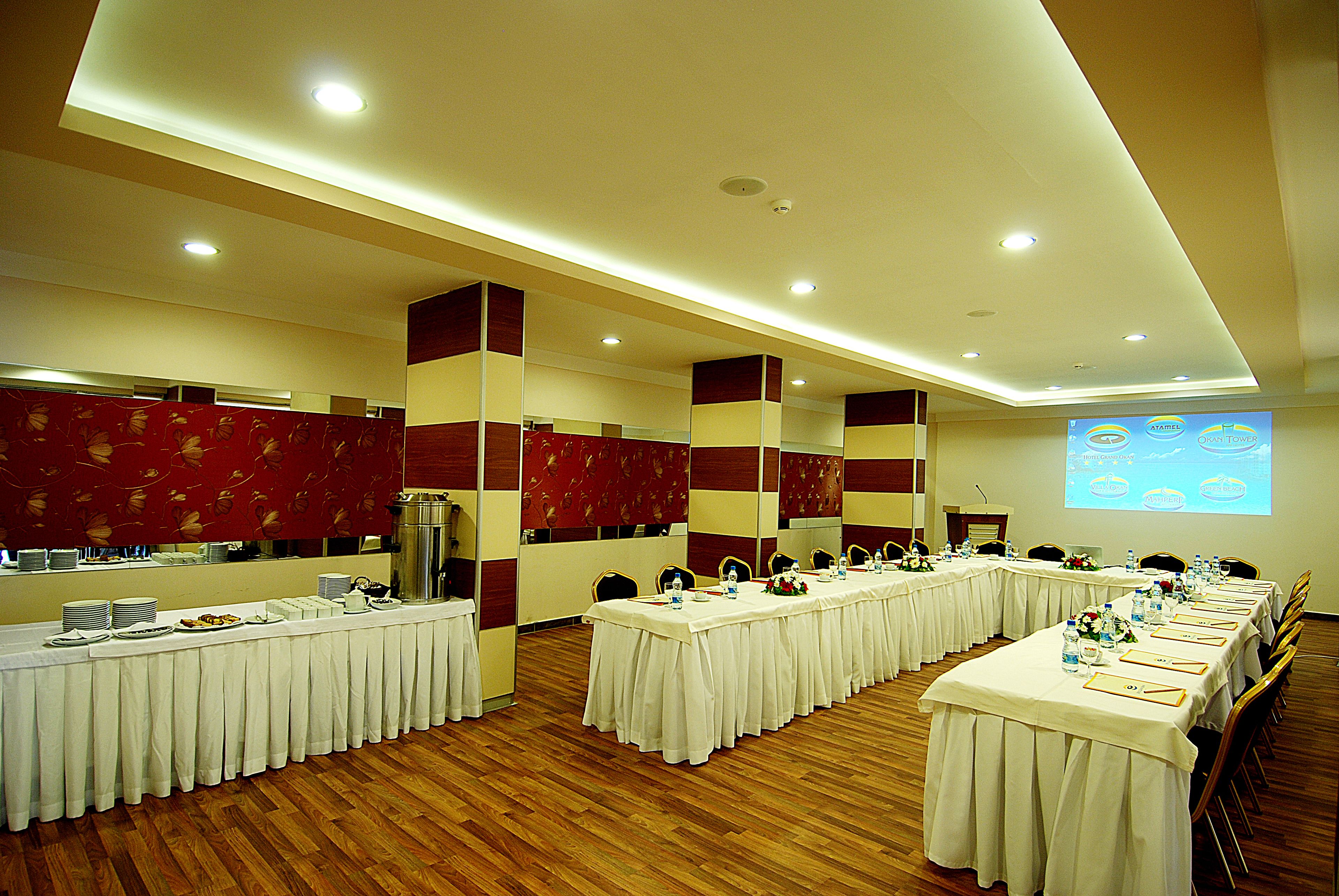 A conference room with long tables set for a meeting, equipped with nameplates, water bottles, and floral centerpieces.