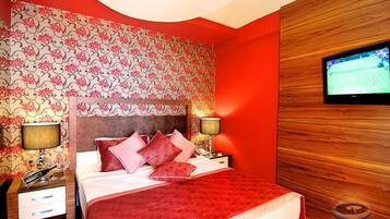 A hotel room with a bed, nightstands, a television, and patterned wallpaper.