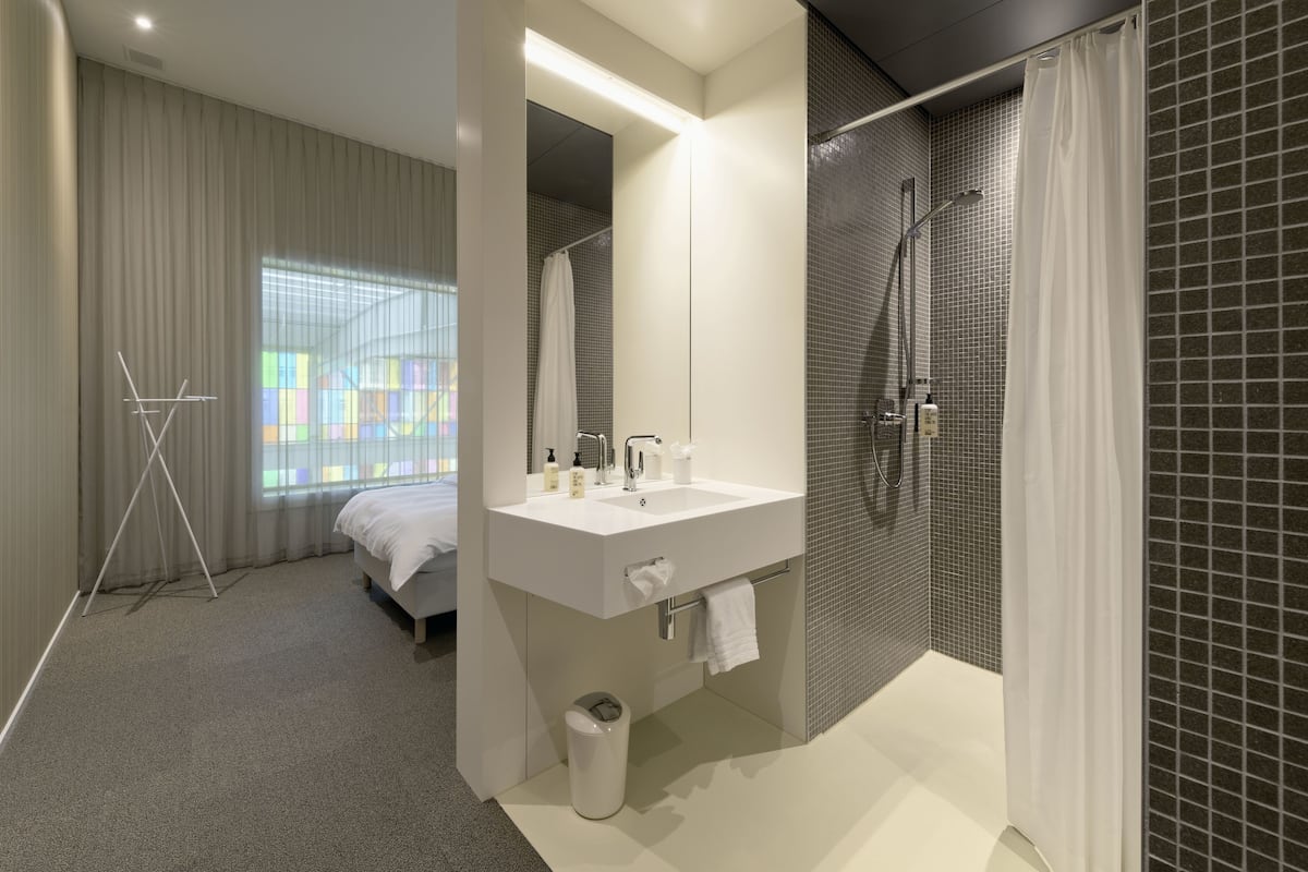 A modern bathroom with a large mirror, a sink, and a shower.
