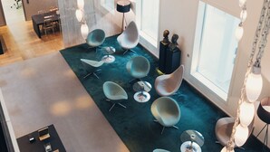 A modern lobby with a teal carpet, contemporary chairs, and a reception desk. - Trafo Hotel (Baden)
