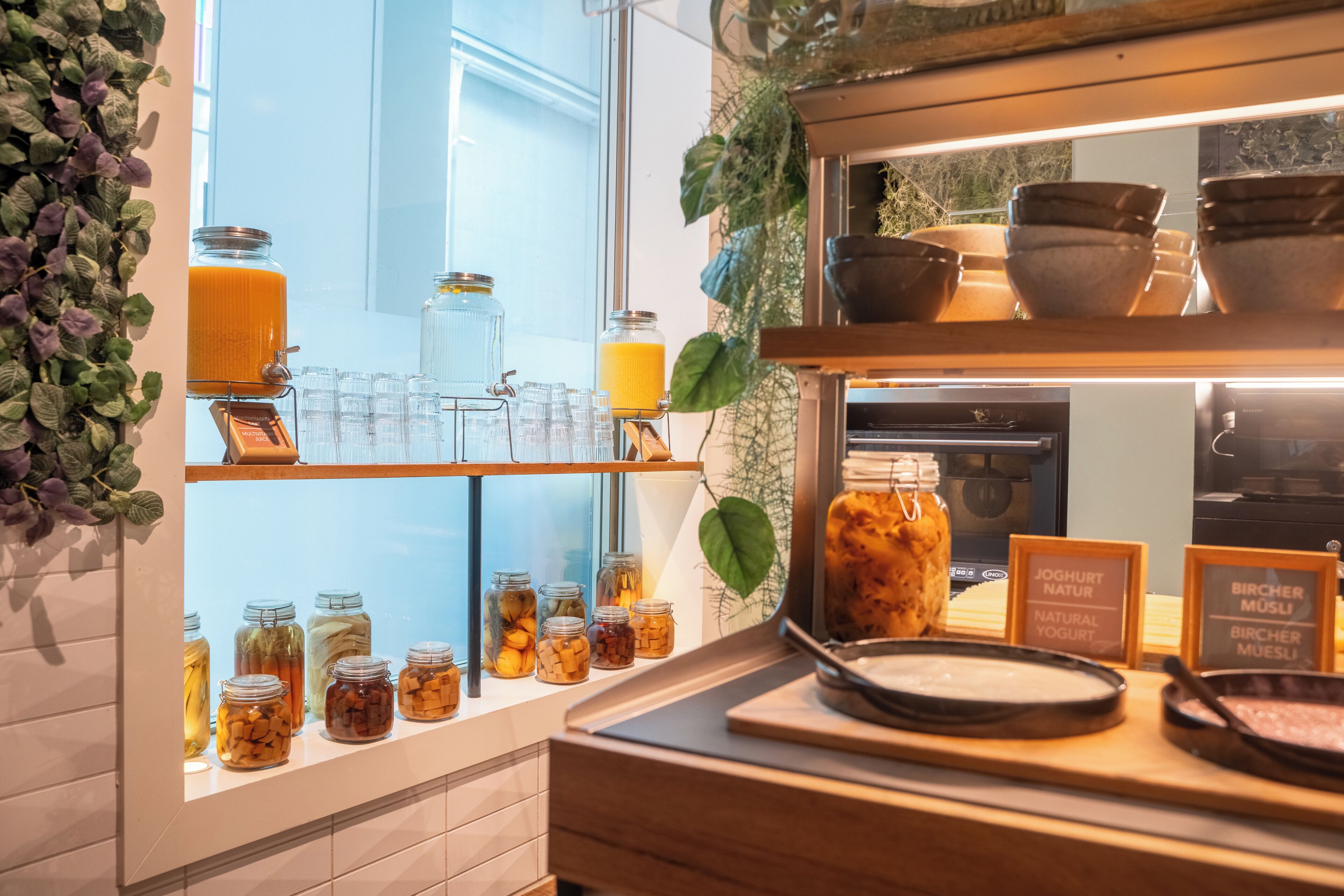 A breakfast bar with various jars of preserves and a selection of bowls and cups.
