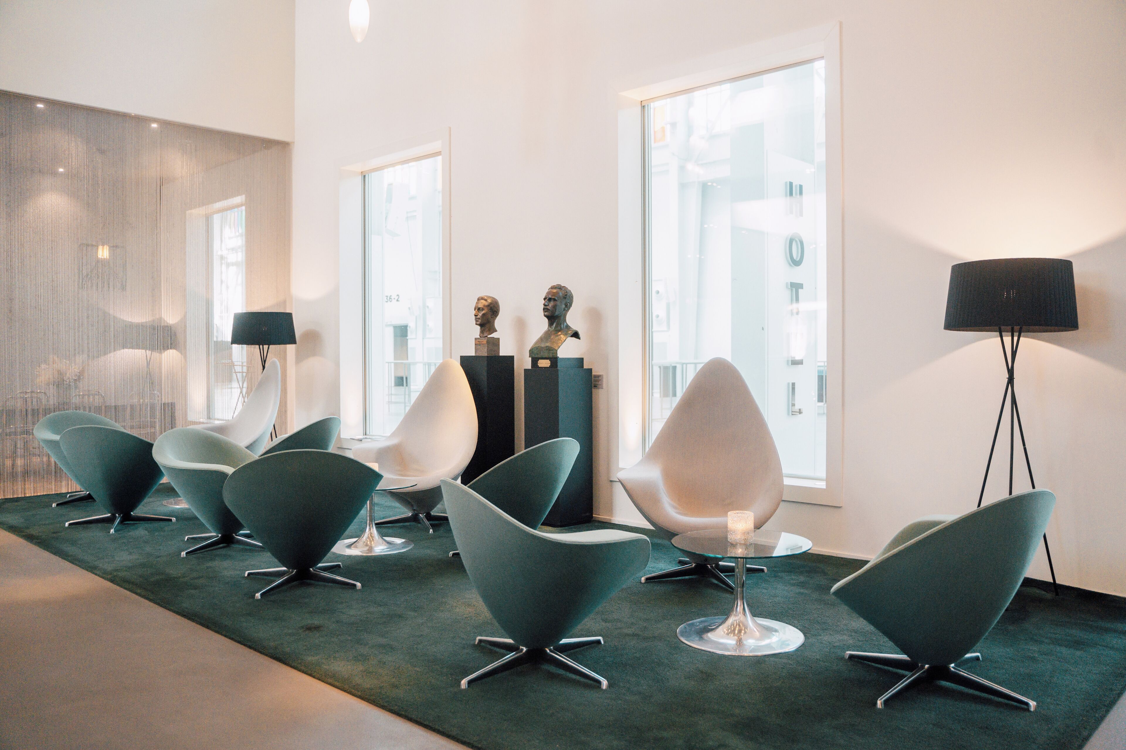 Ein modernes Interieur mit zeitgenössischen Sesseln, einer Glastrennwand und einer Lampe.