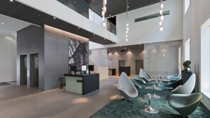 A modern lobby with a reception desk, seating area, and artwork on the wall. - Trafo Hotel (Baden)