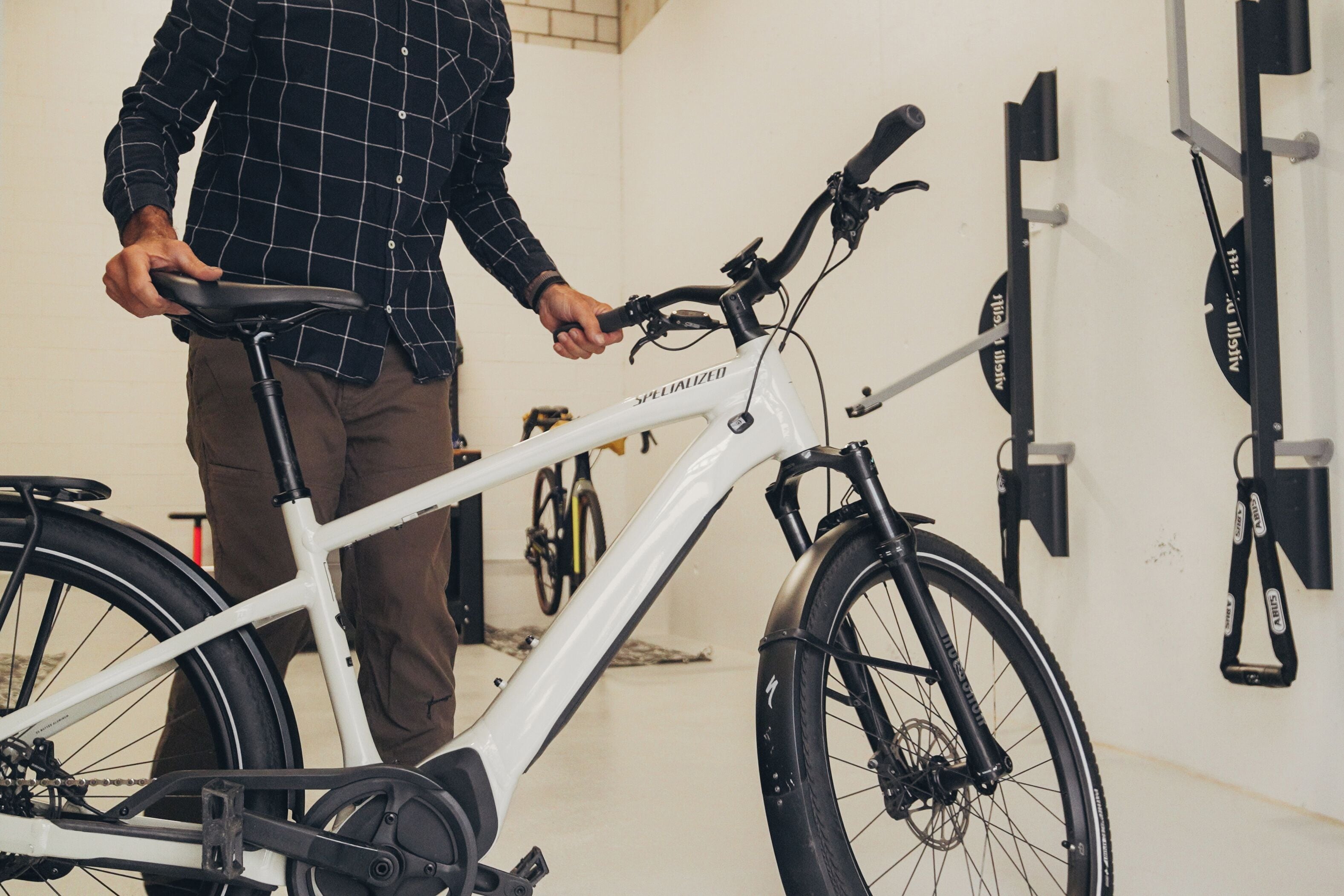 A person standing next to a white bicycle with a handlebar and pedals.