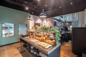 Un área de bufé con diversas opciones de comida, un refrigerador y un espacio de comedor con mesas y sillas.