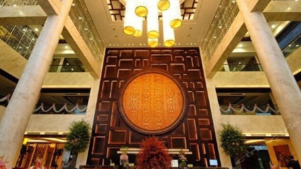 Un vestíbulo con un gran muro decorativo circular, una araña y un mostrador de recepción.