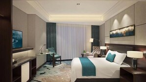 Una habitación de hotel moderna con una cama grande, un escritorio con una computadora portátil, una silla, una mesita de noche con una lámpara y un televisor en la pared.
