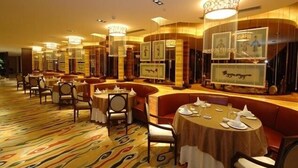 Un restaurante con mesas redondas, cabinas acolchadas y obras de arte enmarcadas en las paredes.