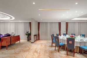 Une salle de conférence dotée d’un sol en marbre, de tables rondes, de chaises et d’un canapé.