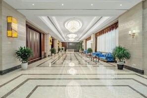 A hotel lobby with a marble floor, seating area, and potted plants. - Fuxing Oriental Boutique Hotel (Chifeng)