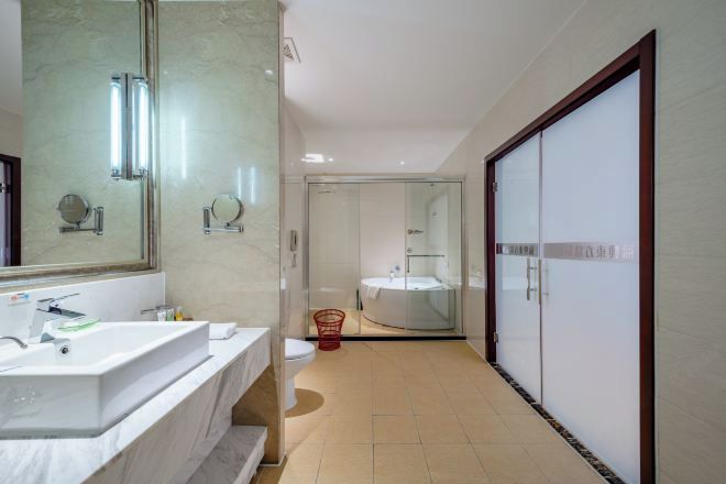 A modern bathroom with a large mirror, a white sink, and a glass shower enclosure.