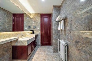 Un baño con paredes de mármol, un lavamanos doble, un espejo y un perchero para toallas.