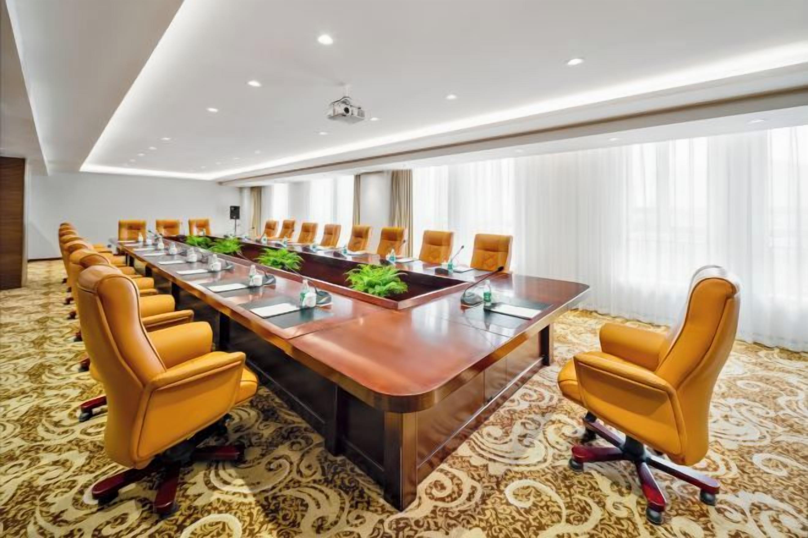 A conference room with a long table, multiple chairs, and a carpeted floor.