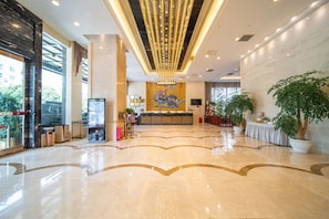 A hotel lobby with a reception desk, a large mural, and potted plants. - Zongheng Hotel (Qiandongnan)