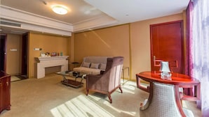 Hotellihuone, jossa on sohva, nojatuoli, sohvapöytä, takka ja ruokapöytä.