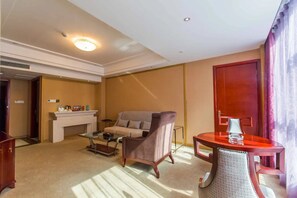 A hotel room with a sofa, armchair, coffee table, fireplace, and a dining table. - Zongheng Hotel (Qiandongnan)