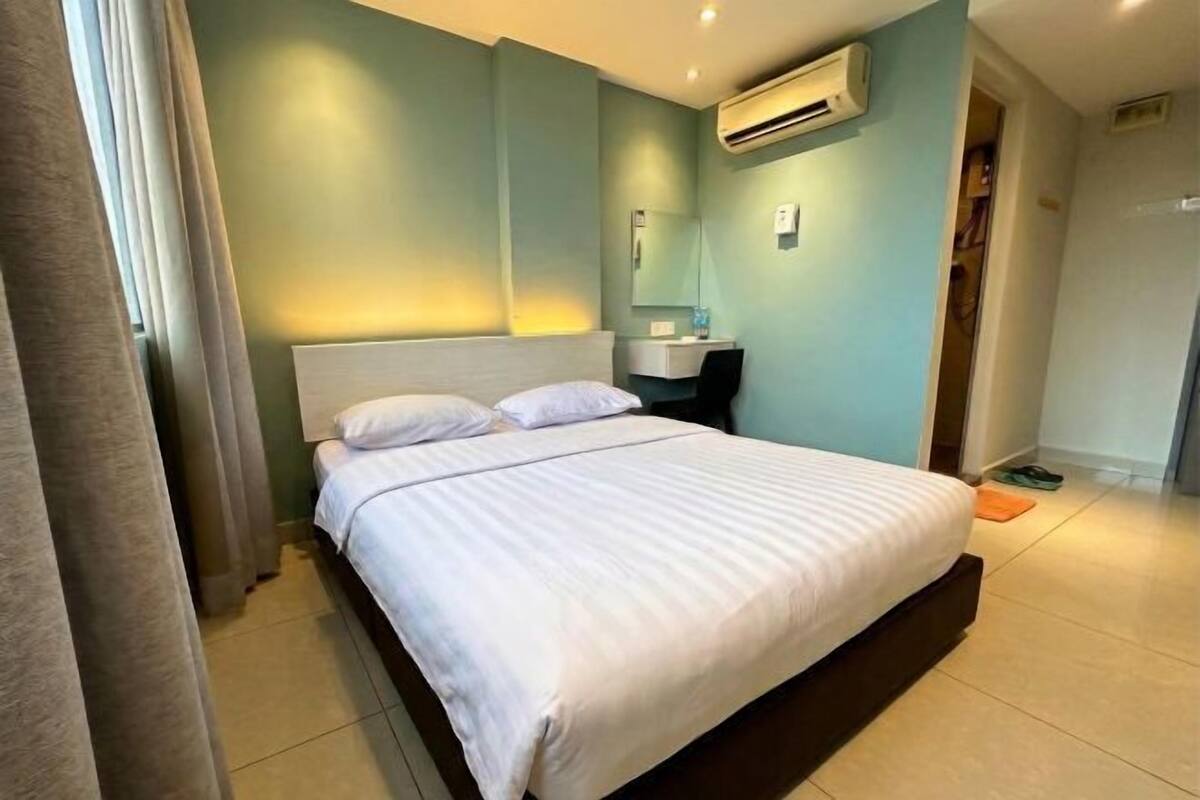 Una habitación de hotel con cama, mesita de noche, espejo y aire acondicionado.