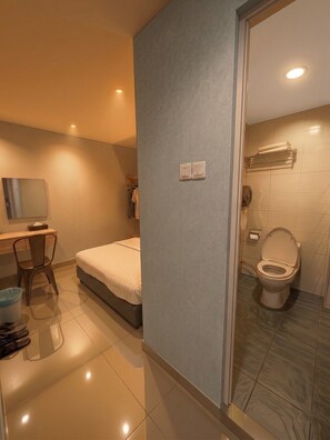 A modern bathroom with a toilet, a shower area, and a small seating area with a chair and a table. - De UPTOWN Hotel @ Damansara Uptown (Petaling Jaya)
