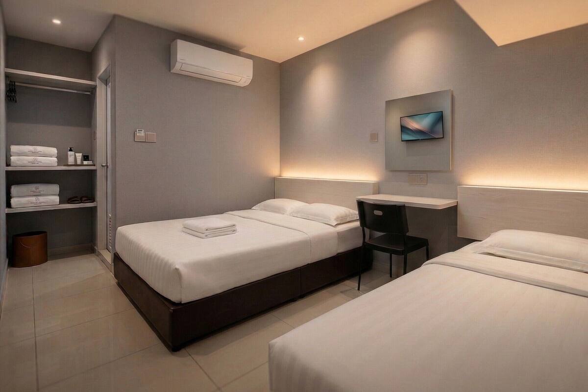 A modern hotel room with two beds, a desk, and a TV.
