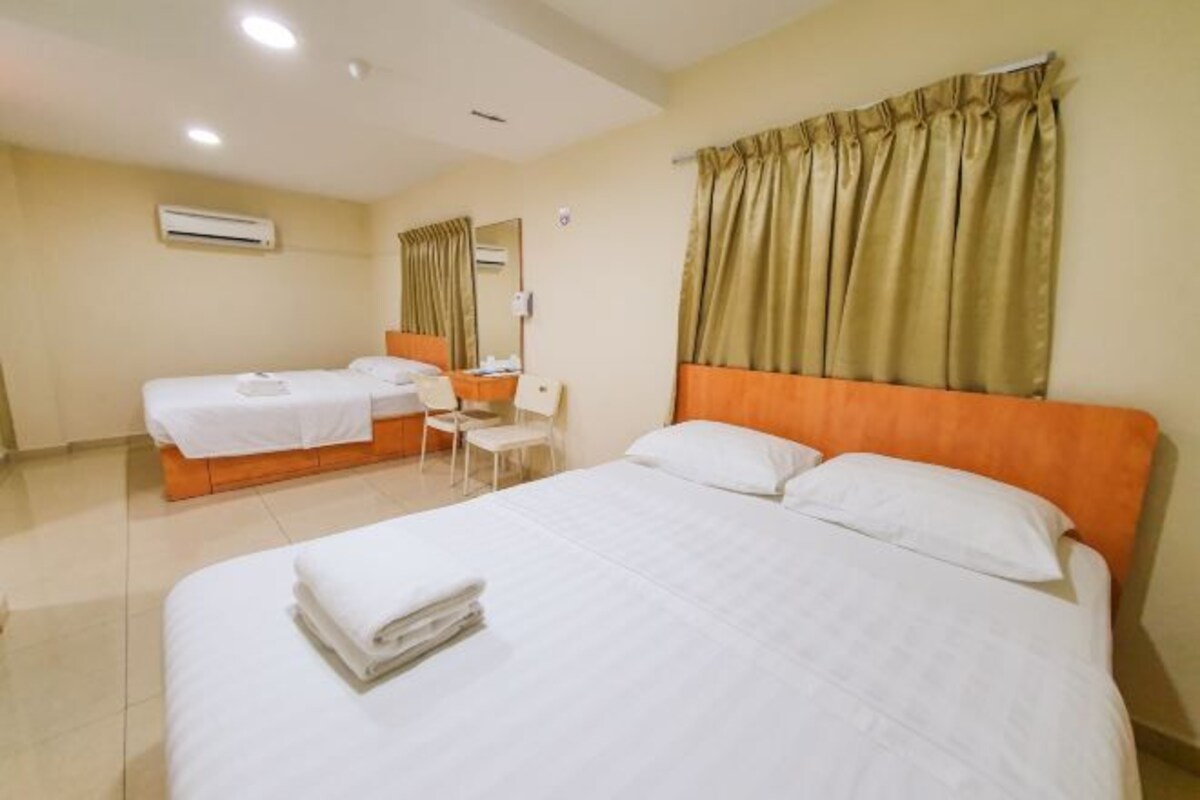 Habitación de hotel con dos camas, un escritorio y aire acondicionado.