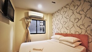 A hotel room with a bed, a TV mounted on the wall, an air conditioning unit, and a window with curtains. - De UPTOWN Hotel @ Subang Jaya (Subang Jaya)