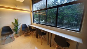 A waiting area with a long bench, several chairs, a potted plant, and a large window with a view of trees and buildings. - De UPTOWN Hotel @ Subang Jaya (Subang Jaya)