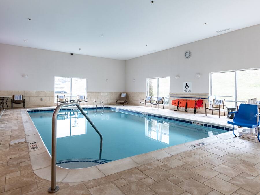 Una piscina con una silla de salvavidas, un elevador de piscina y un reloj en la pared.